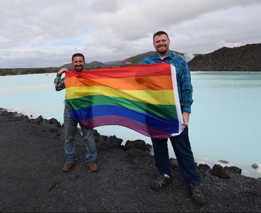 Anthony and Luis with a pride flag at Iceland's Blue Lagoon